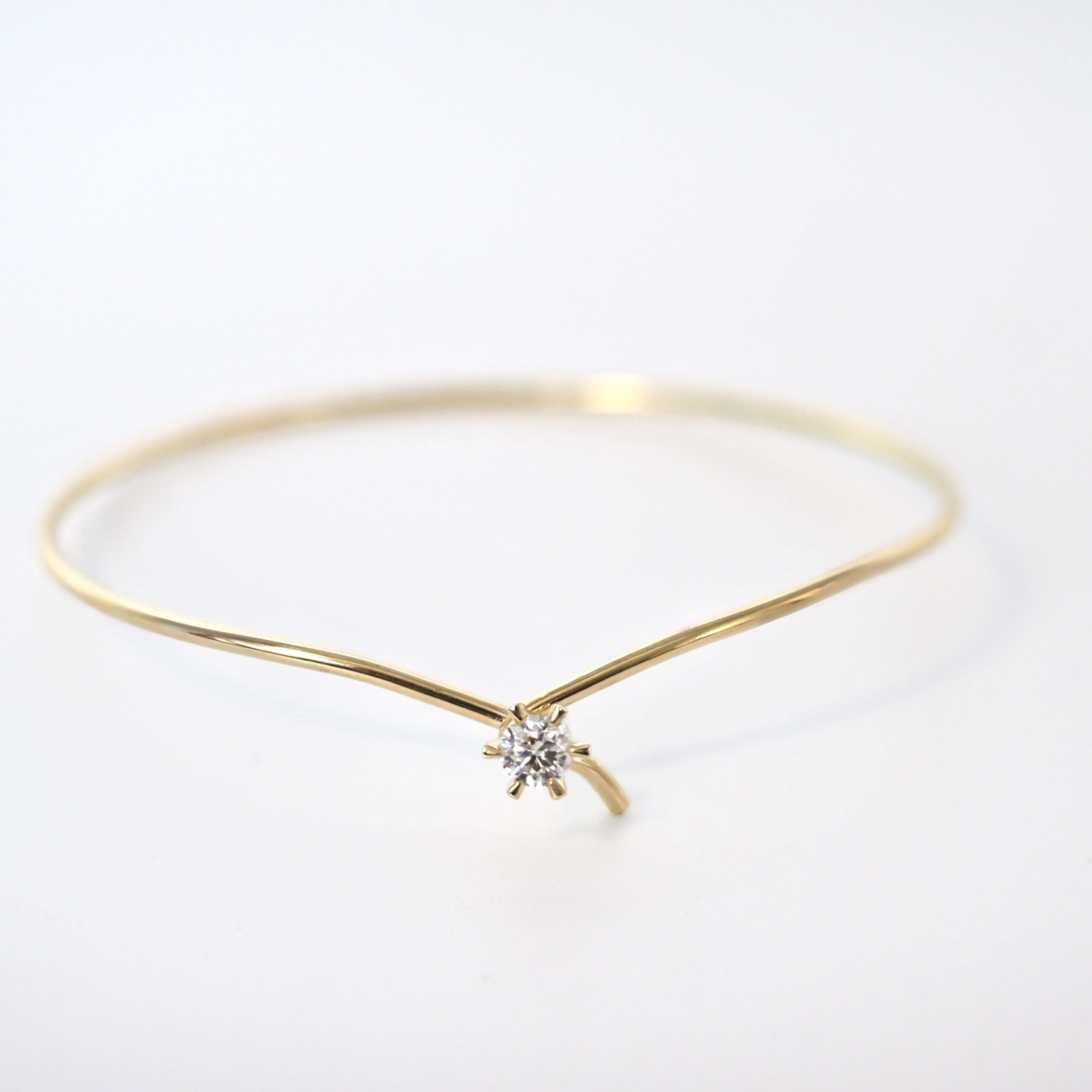 En elegant Jan Jørgensen Present armring i 14 kt. guld. Armringen har et minimalistisk design med en smuk, funklende diamant som midtpunkt, der tilfører et strejf af luksus og tidløs elegance til ethvert look. Perfekt til særlige lejligheder.