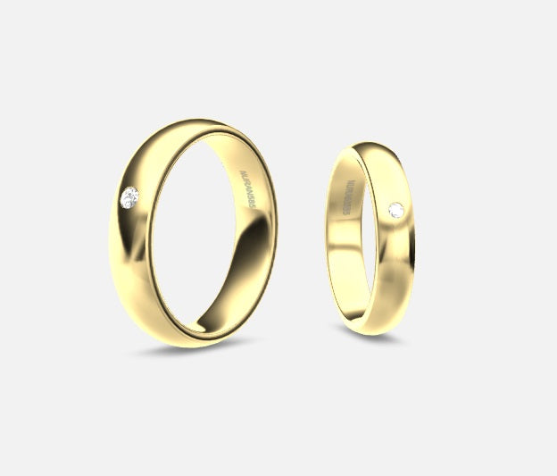Disse Nuran vielsesringe i 14kt guld har et elegant og tidløst design. Med en indfattet diamant i hver ring symboliserer de både enkelhed og luksus, perfekt til par, der ønsker klassisk skønhed på deres bryllupsdag.