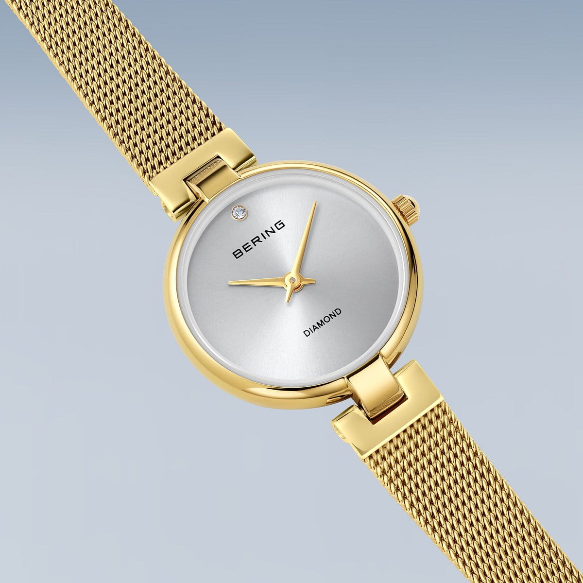 Skråt forfra-visning af Bering Classic 17724‑330 – minimalistisk design med diamantprydet urskive, guldtonet kasse og justerbart milanesearmbånd med sikkerhedslås.