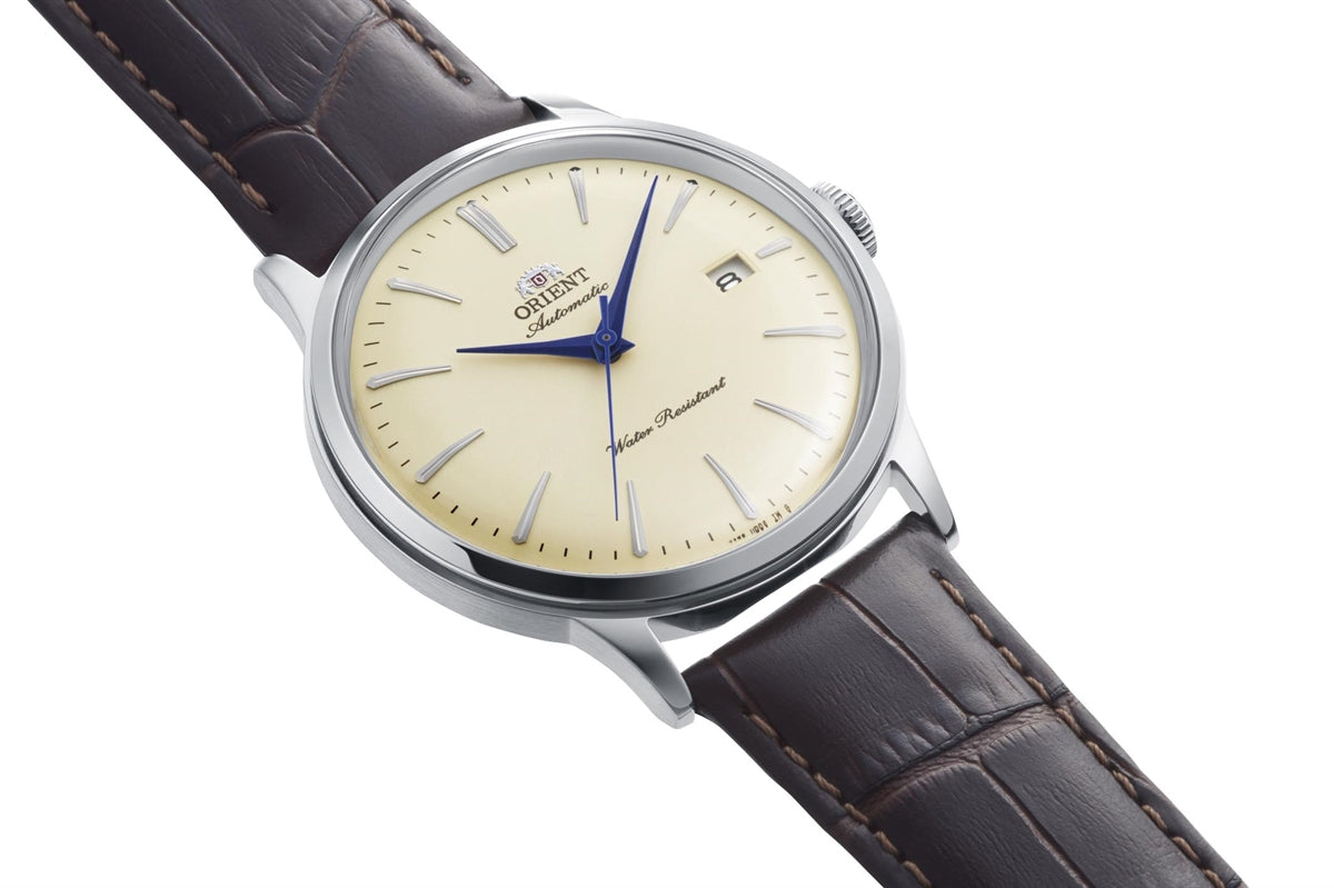 Orient Bambino RA-AC0033Y vist fra siden med sølvfarvet stålkasse, ivory urskive og brun læderrem