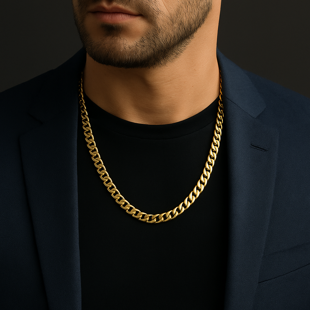 Nærbillede af en mand iført en kraftig guldkæde panser facet , sort t-shirt og mørk navy blazer. Kæden fremstår markant og elegant mod den mørke baggrund og udstråler maskulin stil og eksklusivitet.