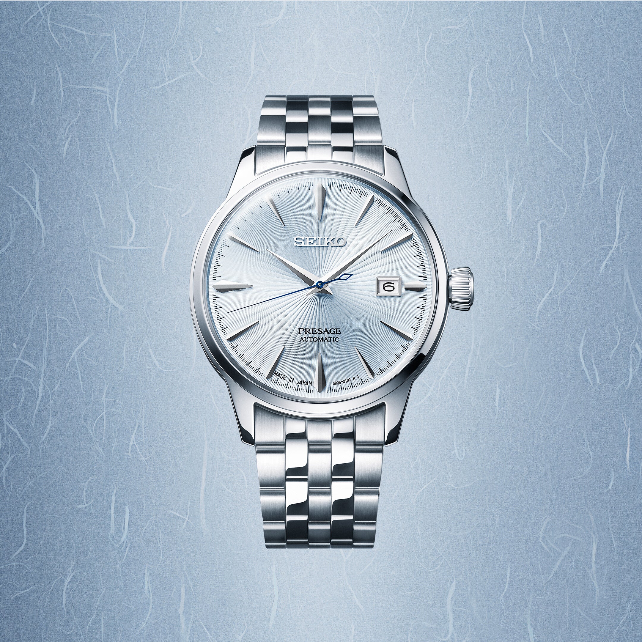 Seiko Presage SRPE19J1 ur med en poleret stålkasse og armbånd. Uret har en lys blå skive med solstrålemønster, datovisning ved 3-tiden, og er mærket 'Automatic' og 'Japan'.