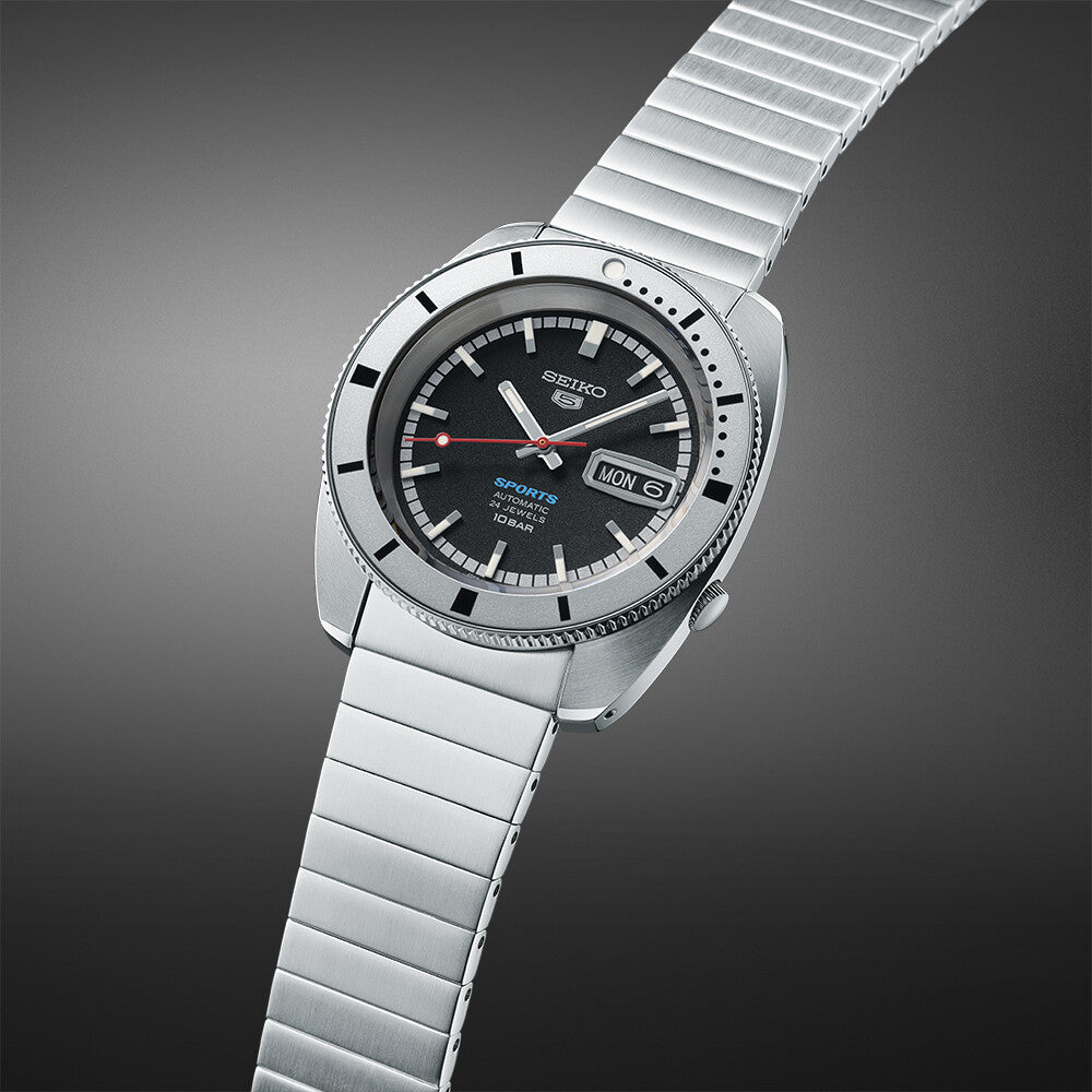 Seiko 5 Sports SRPL05K1 herreur med en sølvfarvet mesh armbånd og urkasse. Skiven er sort med hvid og rød detaljering, inklusiv dag og dato display ved klokken 3