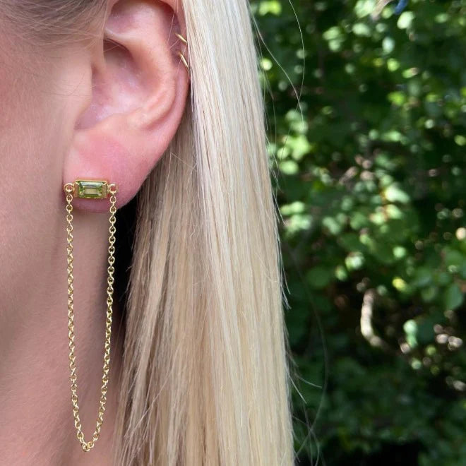 Modelbillede af kvinde som bærer Heiring Square øreringe med kæde. Stenen er en elegant grøn peridot