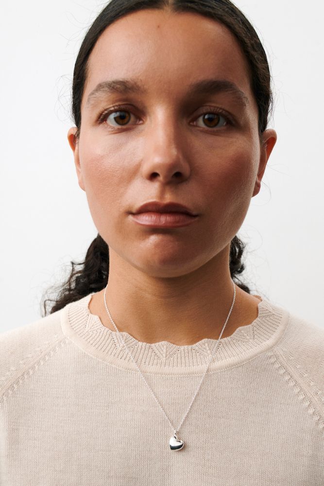 Pernille Corydon - Sweetheart halskæde i sølv med chunky hjertevedhæng, båret af model iført lys striktrøje.