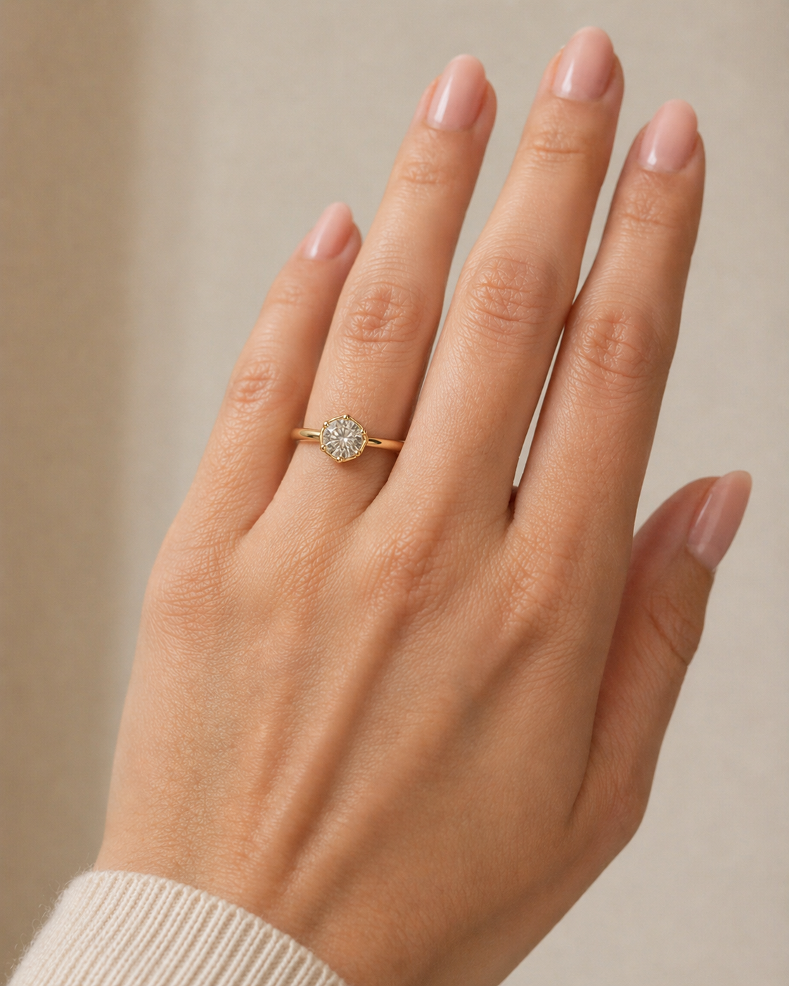 Guldring med rund diamant båret på modelhånd, elegant og enkel ring i varmt guld