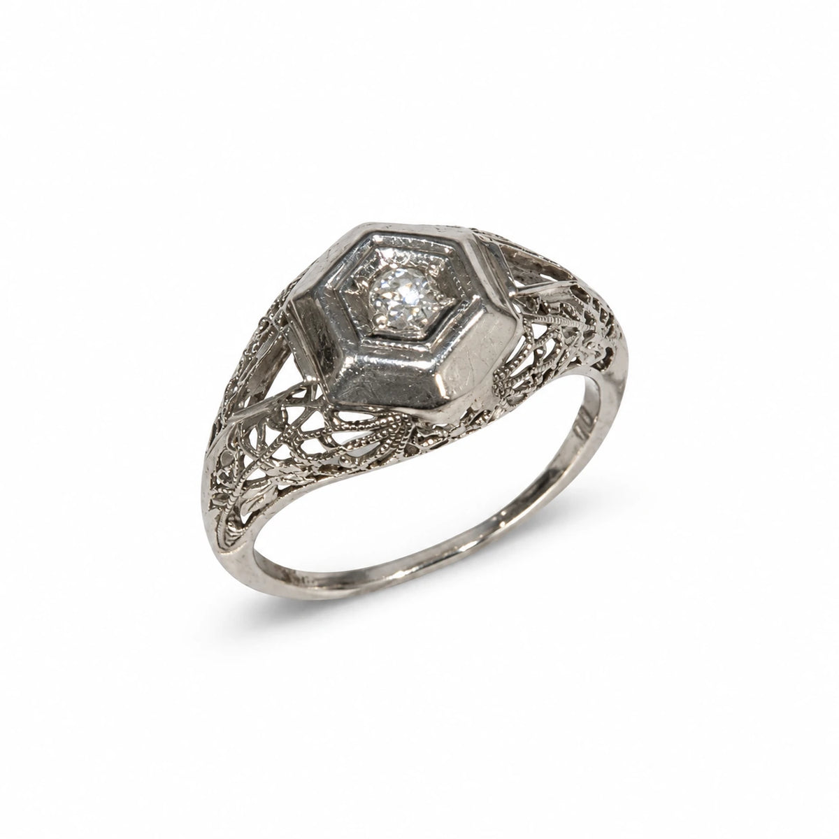 Brugt ring i 18 kt. hvidguld med ca. 0,10 ct. diamant set fra skrå vinkel; filigranpræget mønster og naturlige brugsspor ses – varenr. 46571983 [ai-redigeret]