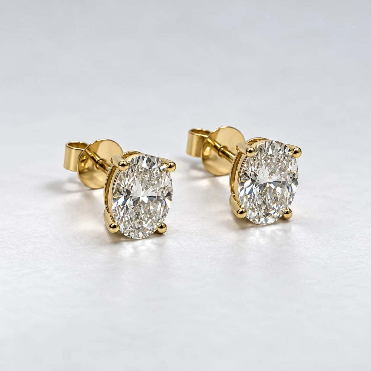 Petersen Jewels Solaris ørestikker i blankpoleret 14 kt guld med 2 × 0,75 ct oval cut labgrown diamanter, set fra skrå vinkel [ai-redigeret]