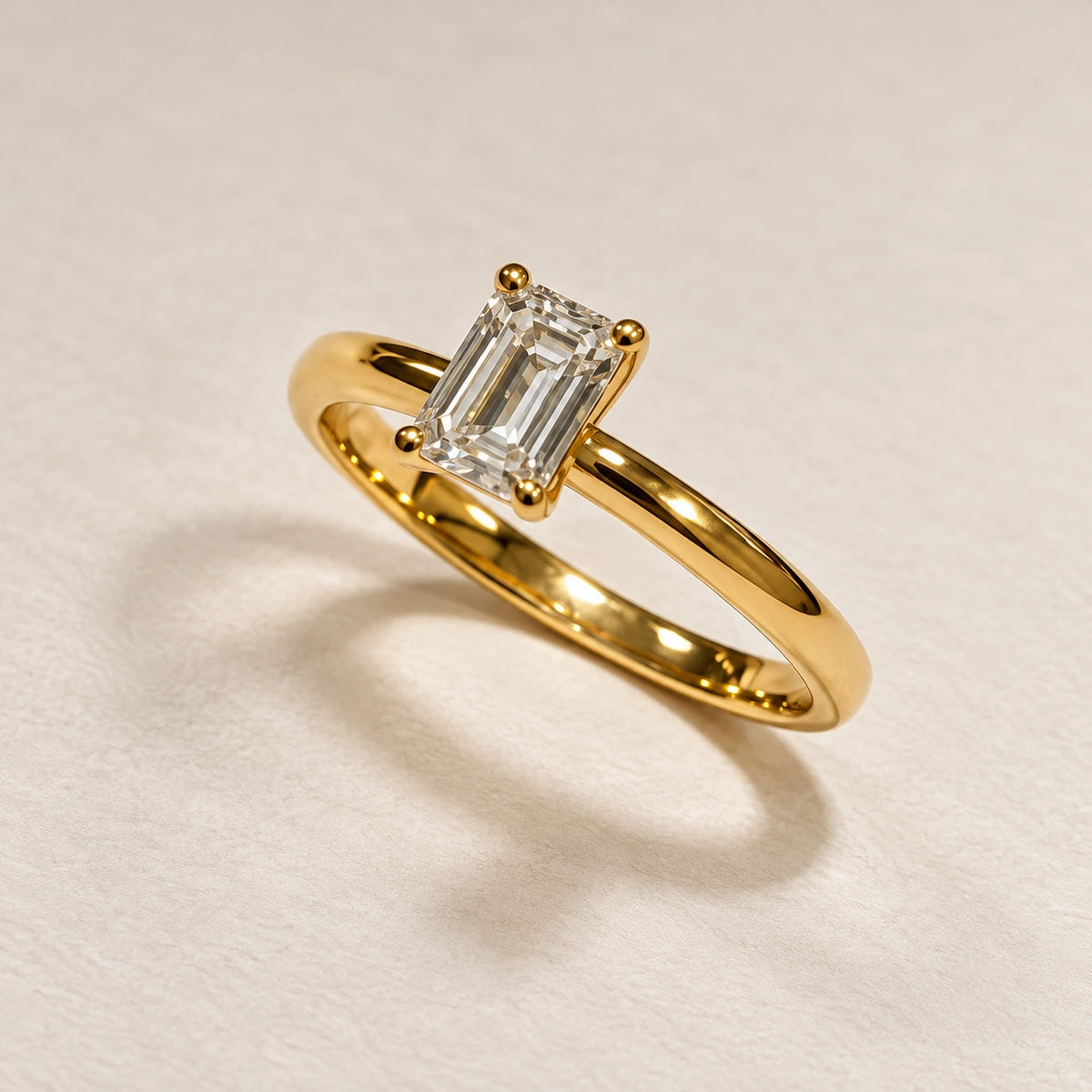 Petersen Jewels Solaris guldring med 0,50 ct emerald cut labgrown diamant i firegriberfatning, vist fra skrå vinkel [ai-redigeret]