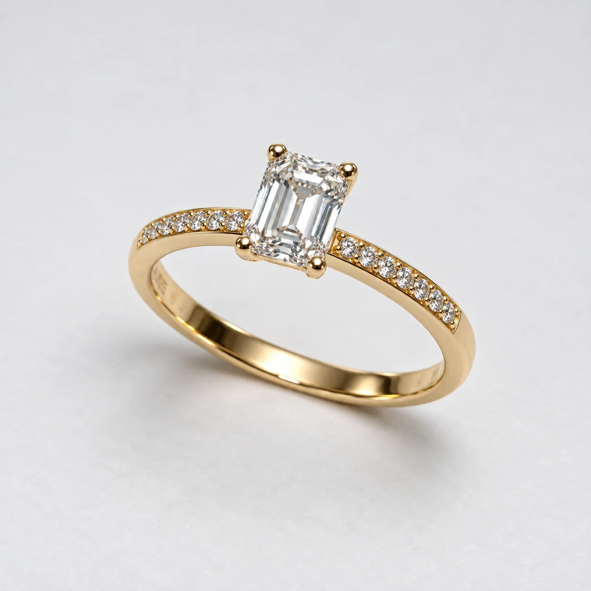 Petersen Jewels solitaire guldring med rektangulær smaragdslibet labgrown diamant og diamanter langs ringskinnen, sidevinkel [ai-redigeret]