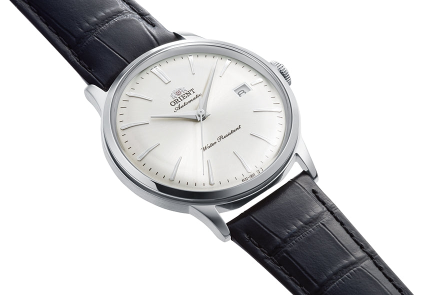 Orient Bambino RA-AC0031S vist fra siden med hvid urskive, dato og sort læderrem